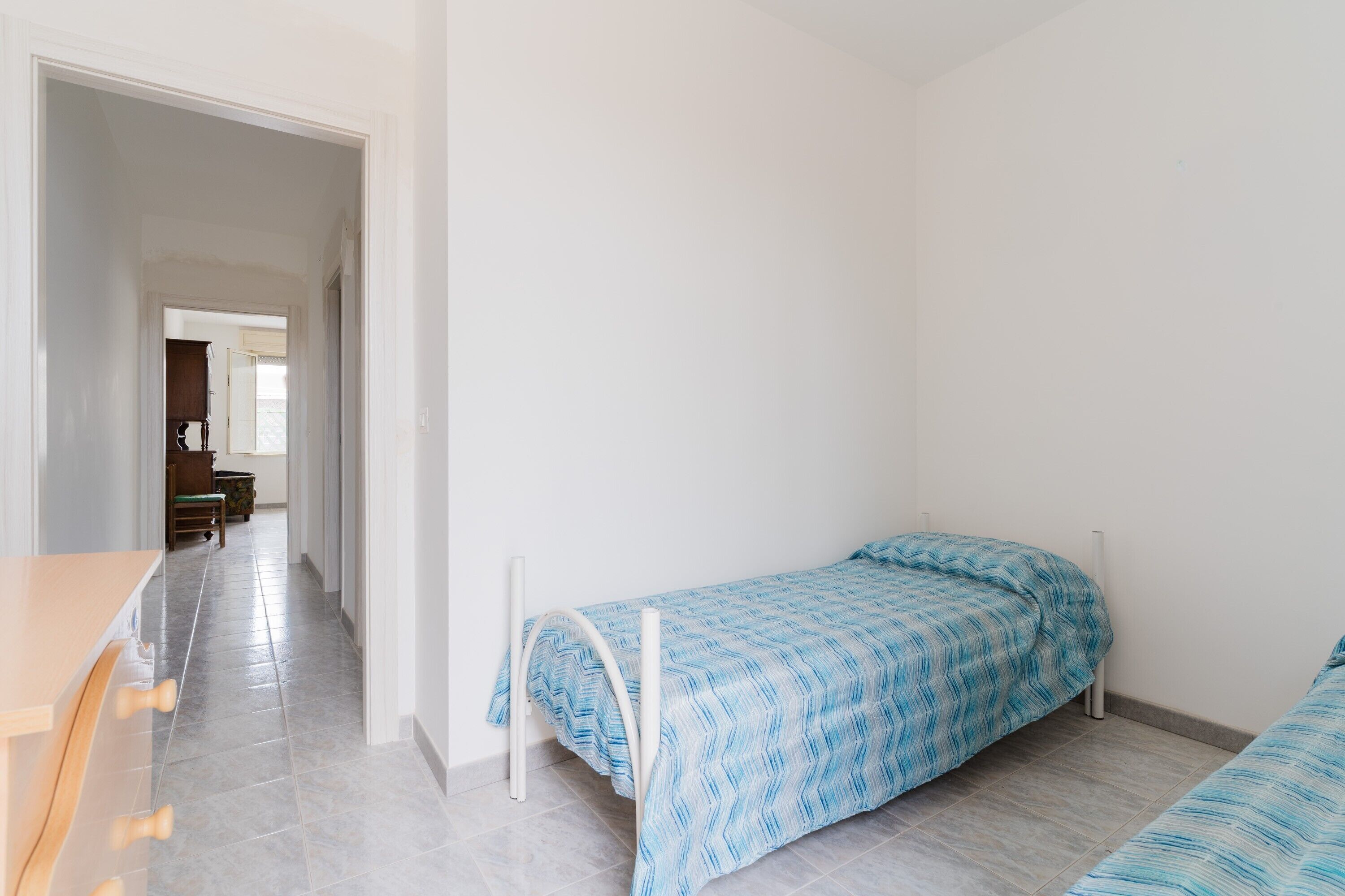 Une chambre avec deux lits simples, un bureau en bois et une chaise.