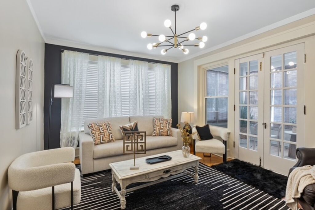 A living room with a sofa, armchairs, a coffee table, and a chandelier.