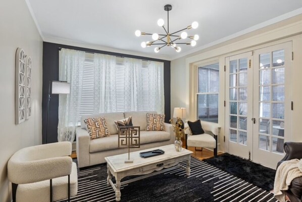 A living room with a sofa, armchairs, a coffee table, and a chandelier.
