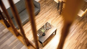 A modern living room with a wooden floor, a grey sofa, and a coffee table with candles and a vase. - Urban Stay by Timisoara BnB Ap 2 (Timisoara)