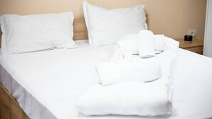 A neatly made bed with white linens and pillows, a wooden headboard, and a small bedside table with a black object on it. - Urban Stay by Timisoara BnB Ap 2 (Timisoara)