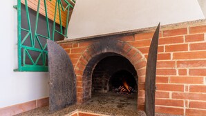 Una chimenea de ladrillo con un marco de ventana verde, una losa de piedra y una puerta de madera.