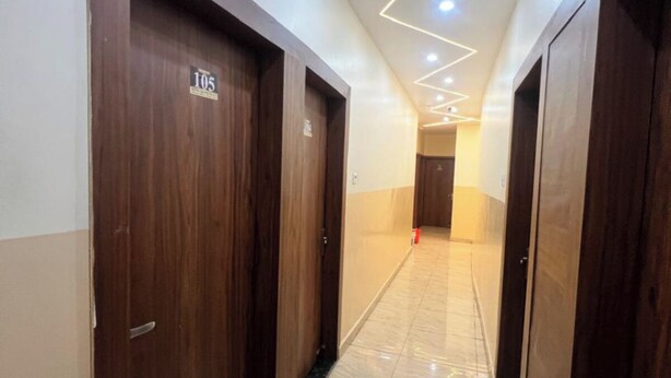 A hotel corridor with wooden doors, numbered 105, and a tiled floor. - Hotel Silver Palace (Kanpur)