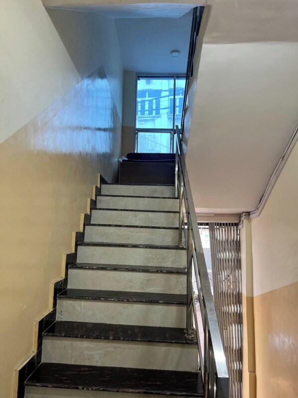 Un escalier avec des rampes en métal et une vue sur l’extérieur par une fenêtre.