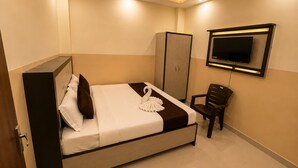 Ein Hotelzimmer mit einem Bett, einem Kleiderschrank, einem Sessel und einem flachbildfernseher an der Wand.