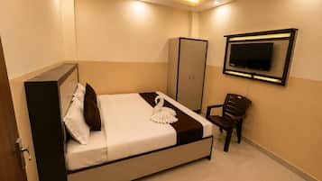 A hotel room with a bed, a wardrobe, a chair, and a flat-screen TV mounted on the wall.