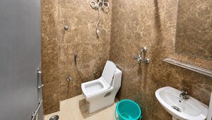 A bathroom with a toilet, bidet, sink, and a handheld showerhead. - Hotel Silver Palace (Kanpur)