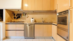 Una cocina con armarios de madera, lavavajillas, estufa y fregadero.