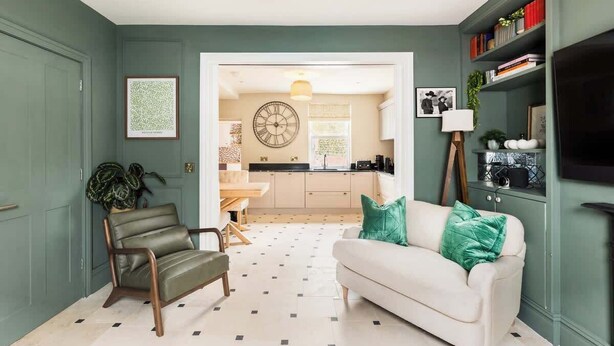 A living room with a sofa, a chair, a coffee table, and a bookshelf. - Well Located, Cheltenham 4 Bed Townhouse & Parking (Gloucestershire)