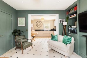 A living room with a sofa, a chair, a coffee table, and a bookshelf. - Well Located, Cheltenham 4 Bed Townhouse & Parking (Gloucestershire)