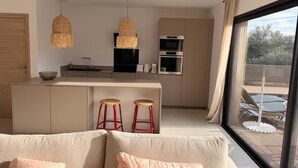 Una cocina moderna con una isla central, dos lámparas colgantes y un ventanal con vistas al exterior.