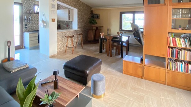 A spacious living area with a sofa, ottoman, and a bookshelf. - Holiday Home 'Dall'alba Al Tramonto' with Private Terrace, Wi-Fi and Air Conditioning (Alezio)