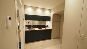 A modern kitchen with dark cabinetry, a stainless steel sink, and a built-in oven. - Triple room 5 minutes from Castel dell'Ovo (Napoli)