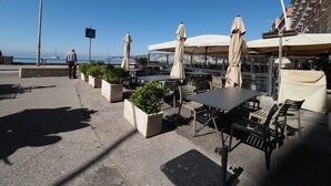 An outdoor café with tables and chairs, umbrellas, and potted plants. - Triple room 5 minutes from Castel dell'Ovo (Napoli)
