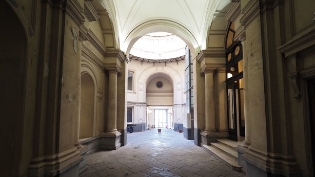 A corridor with classical architecture, featuring columns and arches, leading to a large open space with a high ceiling. - Triple room 5 minutes from Castel dell'Ovo (Napoli)