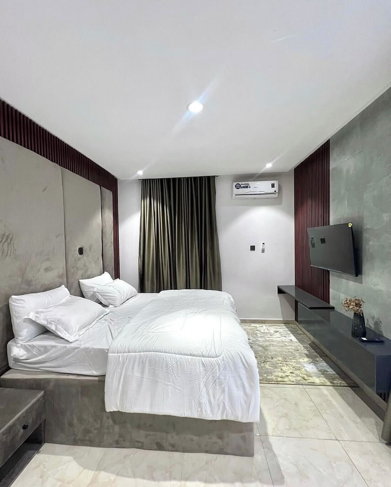 A modern bedroom with a bed, a TV, and an air conditioning unit.