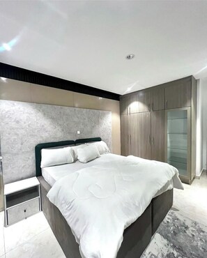 Un dormitorio moderno con una cama grande, armario empotrado y cabecera de mármol.