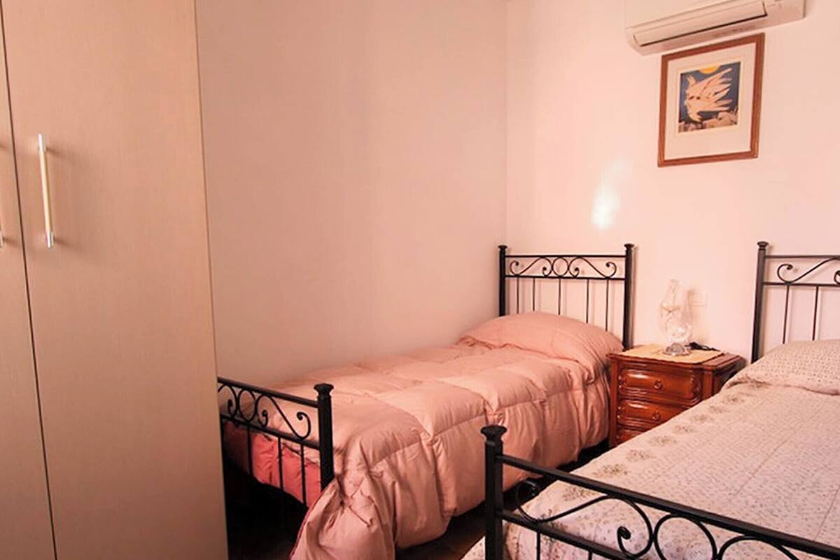 Ein Schlafzimmer mit zwei Betten, einem Kleiderschrank und einem gerahmten Bild an der Wand.