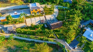 Vist aeri d'un complex turístic amb diversos edificis, una piscina i vegetació tropical exuberant.