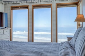 Una camera da letto con un letto grande, una cassettiera e una TV. Dispone di tre finestre con vista sull'oceano.