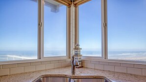 A kitchen with a stainless steel sink and a view of the ocean through large windows. - Logans Beachfront Lodge (Lincoln City)
