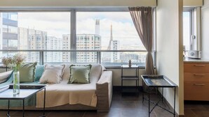Uma sala de estar moderna com um sofá, uma mesinha de centro e vista para a Torre Eiffel através de grandes janelas.