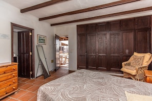 A bedroom with a bed, wooden wardrobe, a chair, and a dresser.