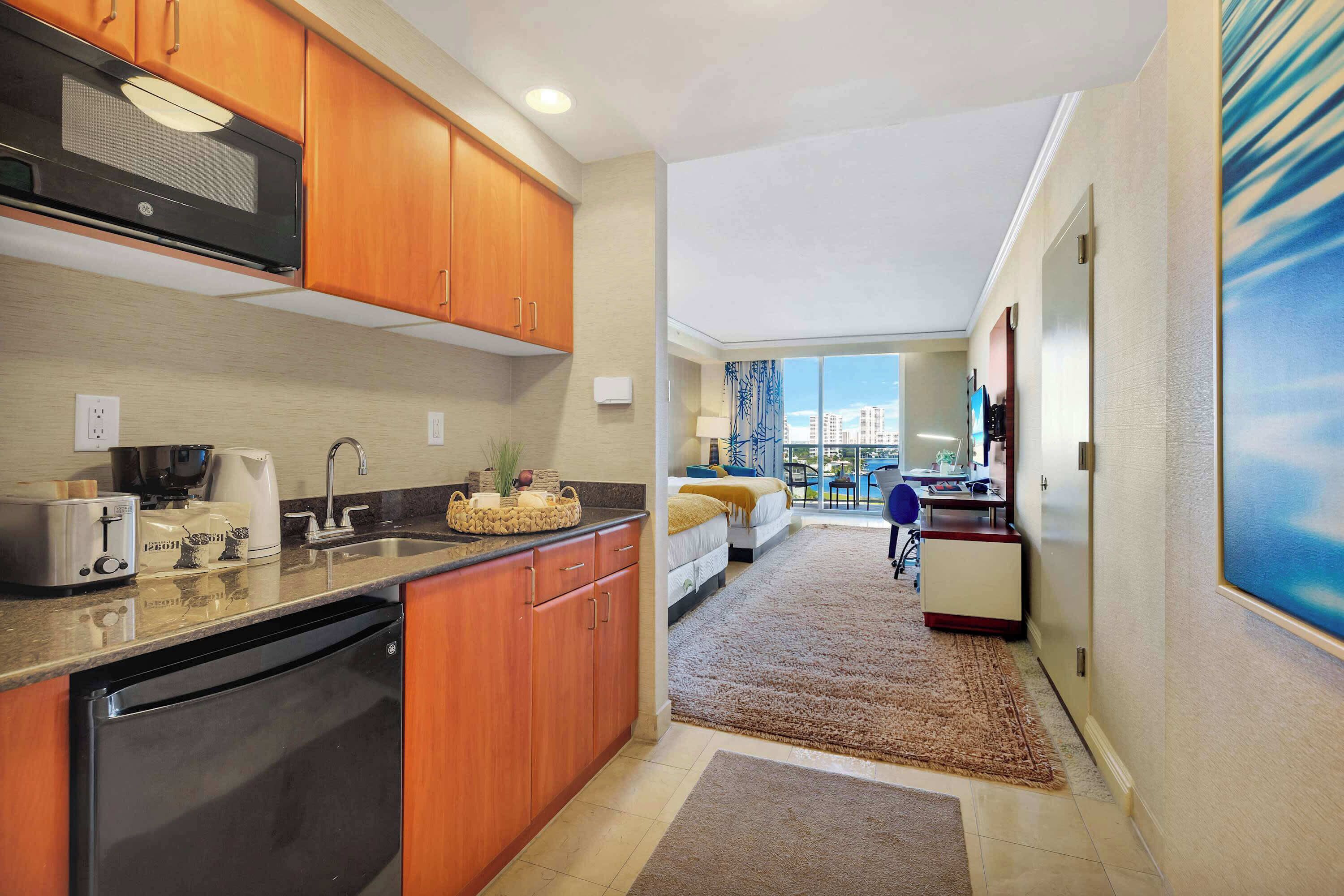 A compact kitchen with wooden cabinets, a built-in microwave, and a dishwasher.