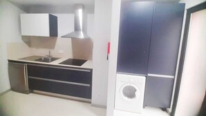 Une cuisine compacte équipée d’un évier, d’une cuisinière et d’un lave-linge encastré.