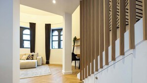 A modern interior with a staircase, a living room with a sofa and curtains, and a dining area. - Luxury Church Conversion in Hale - Sleeps 4 (Altrincham)