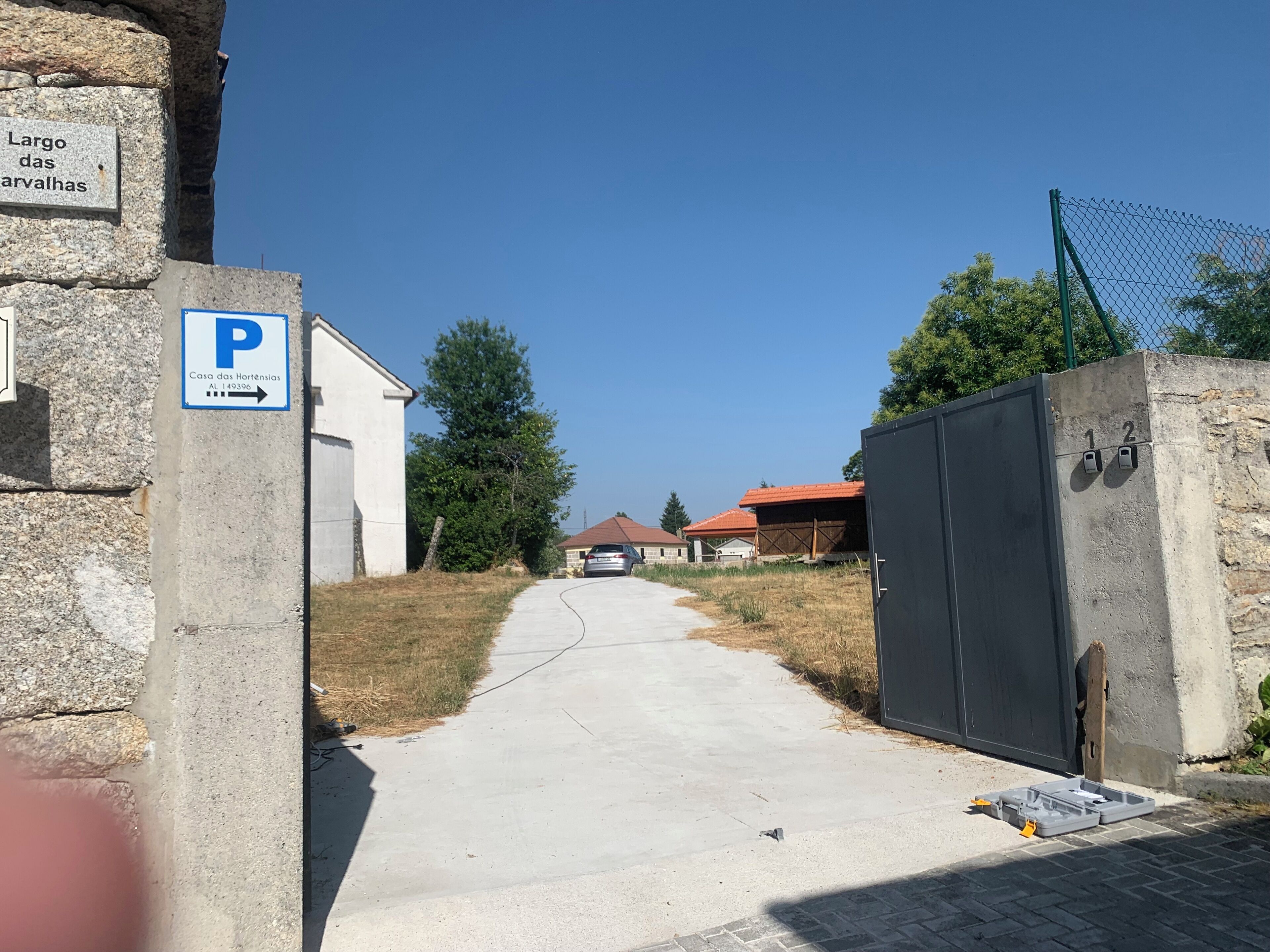 A paved driveway leading to a building with a parking sign.
