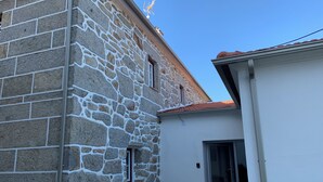 A stone building with a small window and a door, a cobblestone ground, and a clear blue sky. - HYDRANGEA HOUSE (Vila Nova de Paiva)
