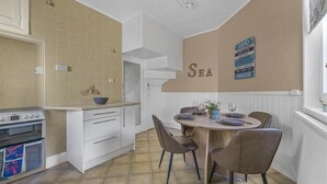 A compact kitchen with a dining area, featuring a round wooden table and four chairs.