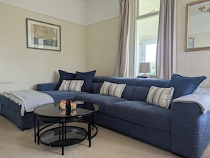 Ein Wohnzimmer mit blauem Sofa, rundem Couchtisch und einem gerahmten Bild an der Wand.