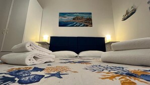 Ein Hotelzimmer mit einem Bett, zwei Nachttischlampen, einem Bild an der Wand und einem gefalteten Handtuch auf dem Bett.