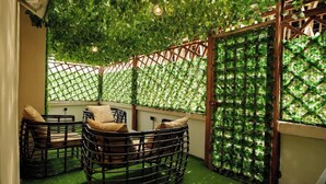 An indoor garden with a seating area featuring wicker furniture and a wooden trellis backdrop. - Akira's  Homes (Abuja)