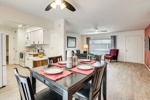 A modern kitchen with white cabinets, a microwave, and a dining area with a wooden table set for four. - Close to Golf! 55-plus Snowbird Escape in Mesa (Mesa)