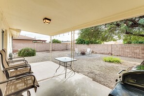 A covered patio with a table and chairs, a barbecue grill, and a car parked nearby. - Close to Golf! 55-plus Snowbird Escape in Mesa (Mesa)