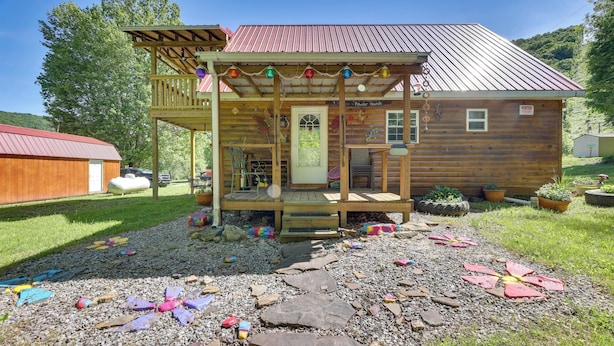 A wooden cabin with a porch, a metal roof, and a gravel ground with colorful stones. - Family Cabin! Close to Greenbrier River & Snowshoe (Cass)