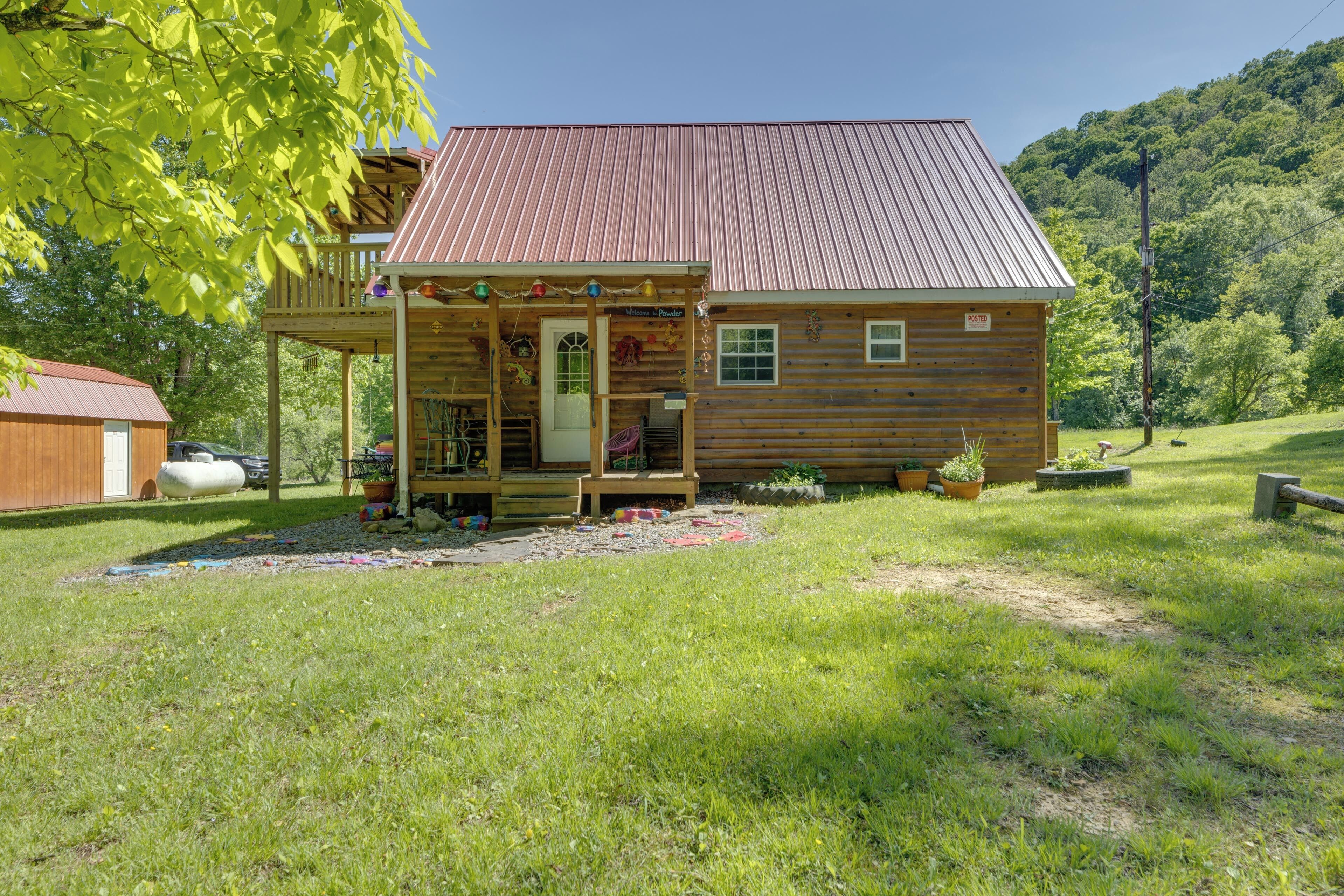 A wooden cabin with a porch, a small deck, and a metal roof.
