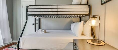 A bunk bed with white bedding, a bedside lamp, and a floral rug.