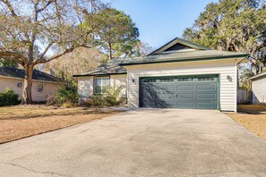 A single-story house with a green garage door, a front yard with a tree, and a driveway. - Dogs Welcome! Savannah Escape w/ Fenced-in Yard (Savannah)