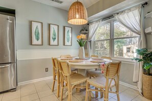 A kitchen with a round dining table, wicker chairs, a stainless steel refrigerator, and framed botanical prints on the wall. - Dogs Welcome! Savannah Escape w/ Fenced-in Yard (Savannah)