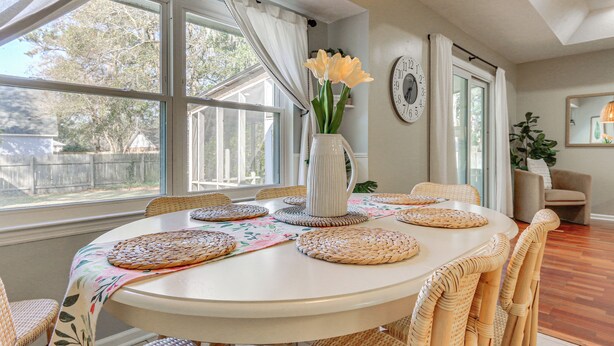 A dining area with a round table, wicker chairs, and a vase with flowers. - Dogs Welcome! Savannah Escape w/ Fenced-in Yard (Savannah)