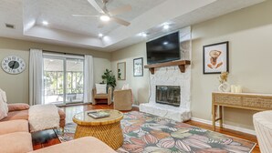 A spacious living room with a fireplace, comfortable seating, and a large flat-screen TV. - Dogs Welcome! Savannah Escape w/ Fenced-in Yard (Savannah)