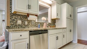 A kitchen with white cabinets, a stainless steel dishwasher, and a tiled backsplash. - Dogs Welcome! Savannah Escape w/ Fenced-in Yard (Savannah)