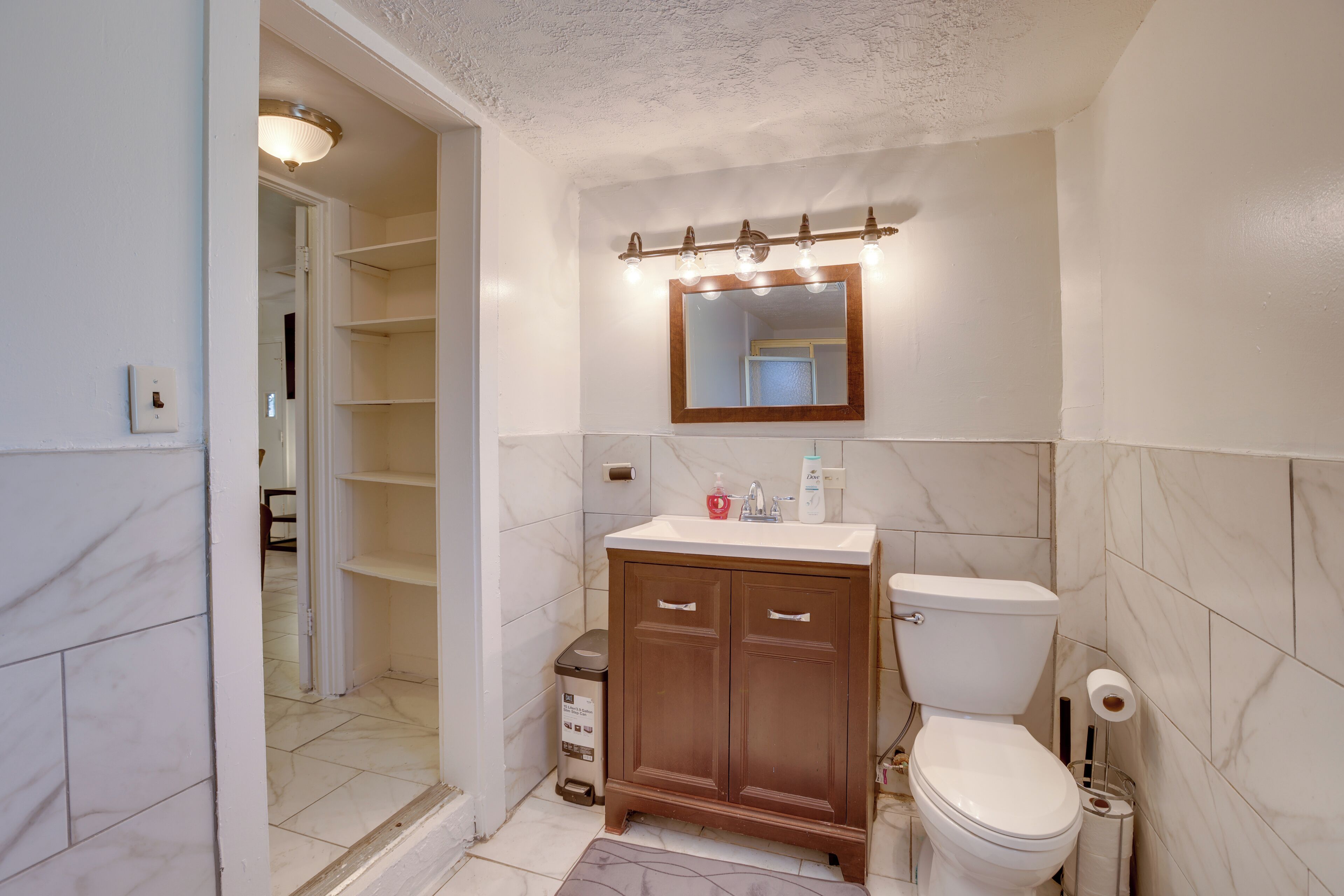 Un baño con inodoro, tocador y espejo con iluminación.