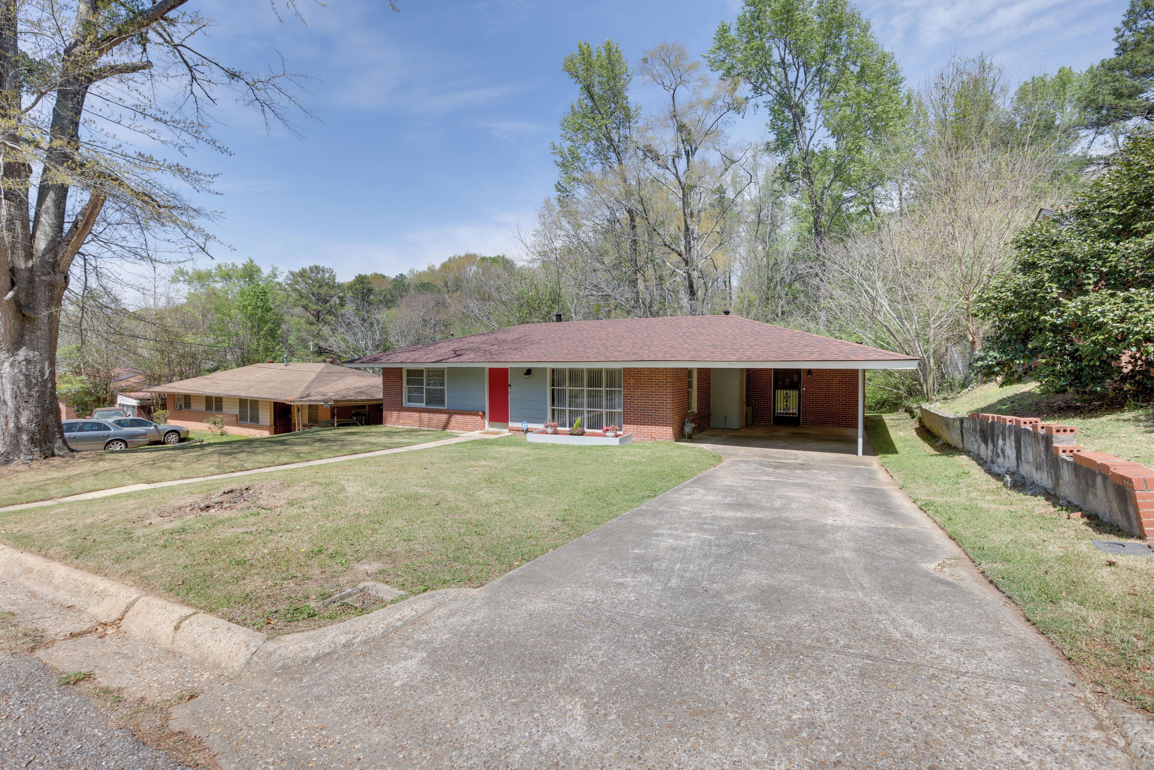 A single-story building with a red roof, a front porch, and a paved driveway.
