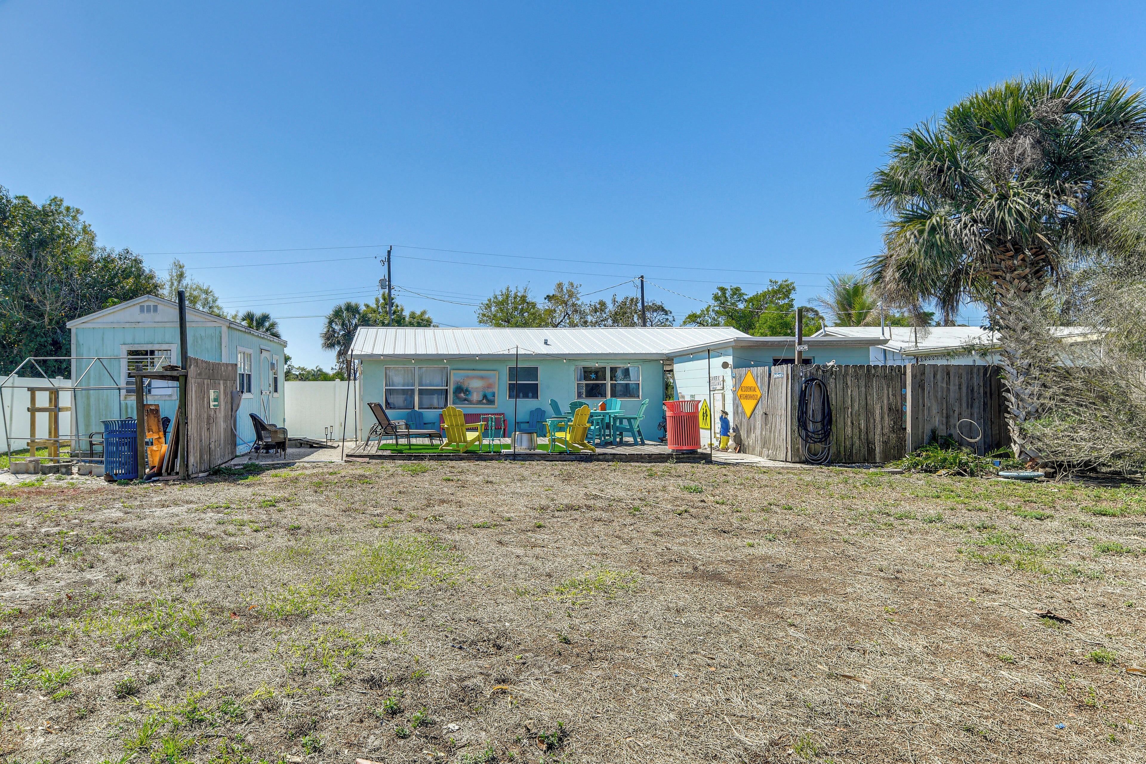 A residential property with a detached house, a fenced yard, and a palm tree.