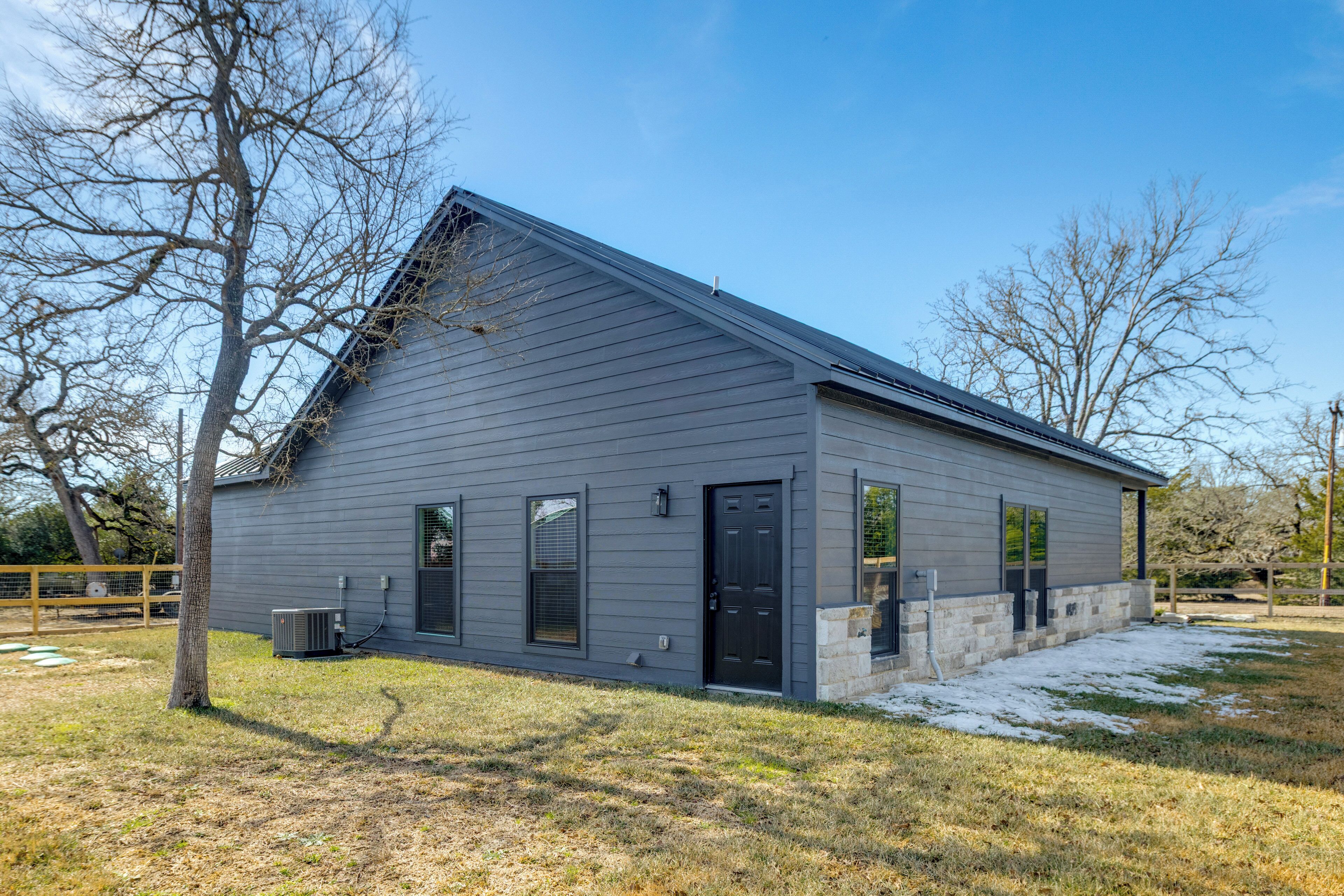 A single-story building with a grey exterior, a black front door, and a small porch area.